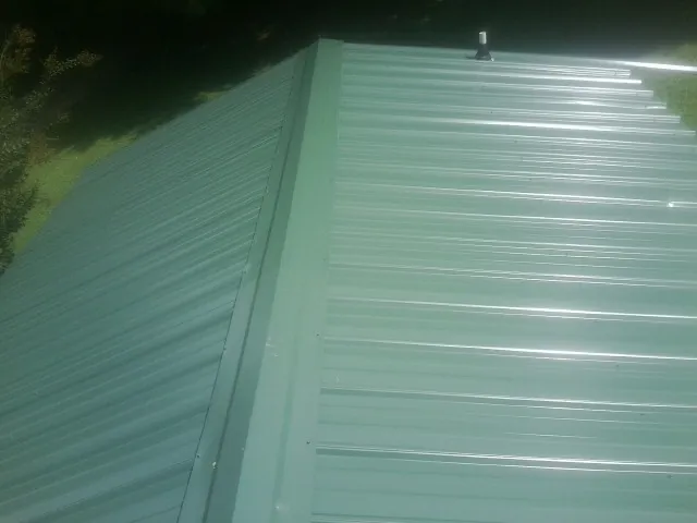 New green metal panels meeting at the ridge of a roof — Flat Roof Repair work by our crew in Fiatt