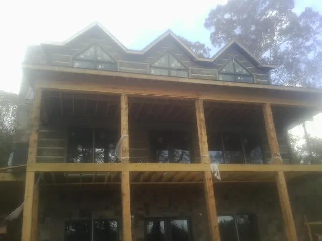 Dormers and porch framing on a large log home under construction — Roof Coating work by our crew in Fiatt