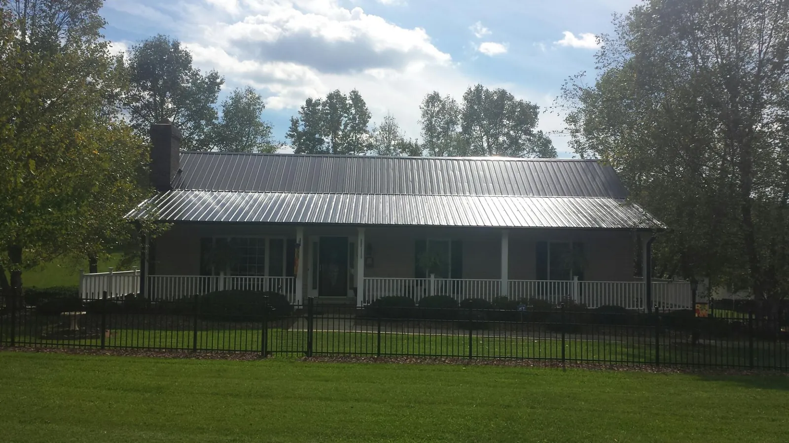 Gray metal roof on a brick ranch with a full width front porch — Gutter Guard Installation work by our crew in Fiatt