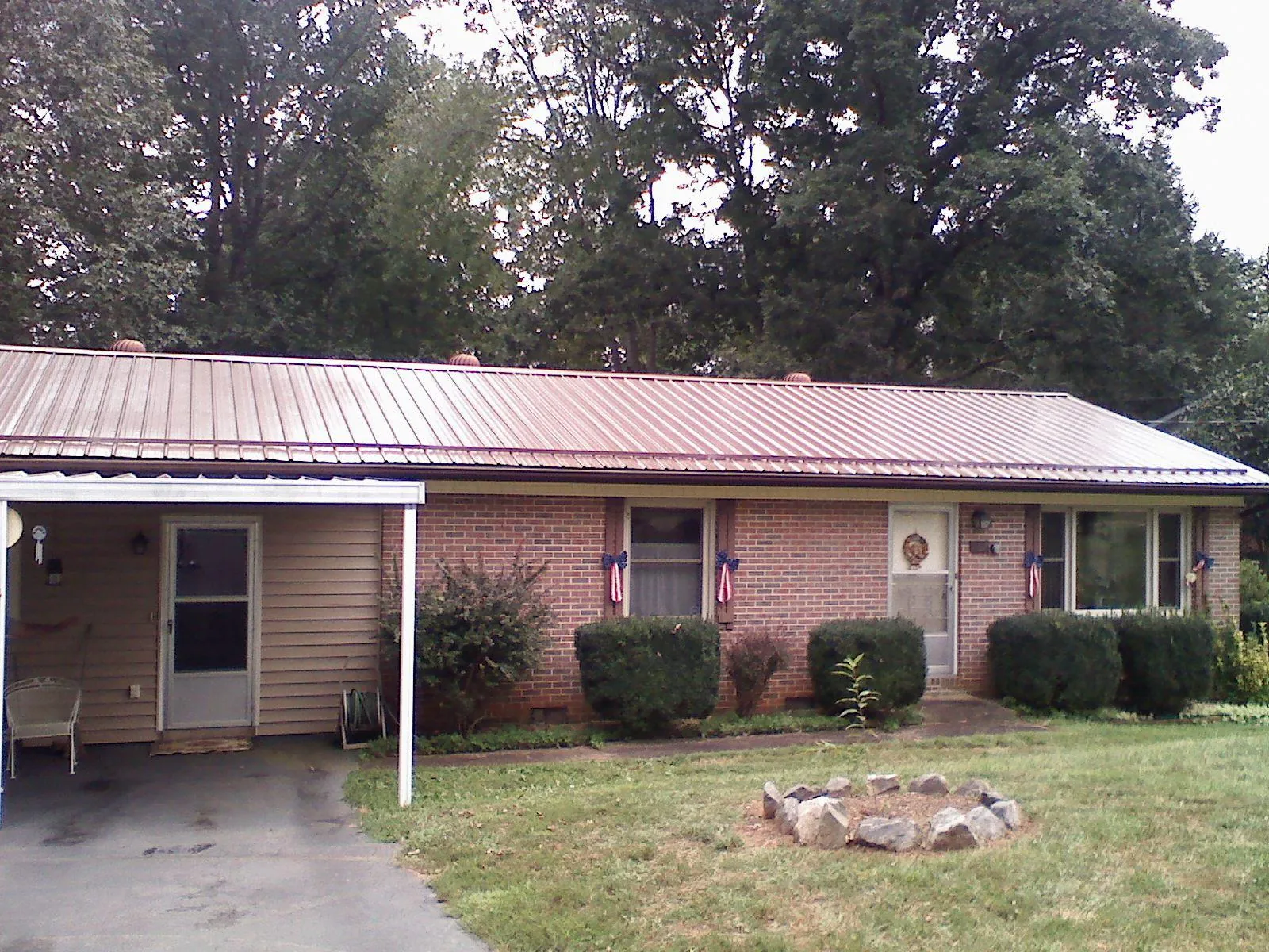 Bronze metal roof and carport on a brick ranch home — Roof Repair work by our crew in Fiatt