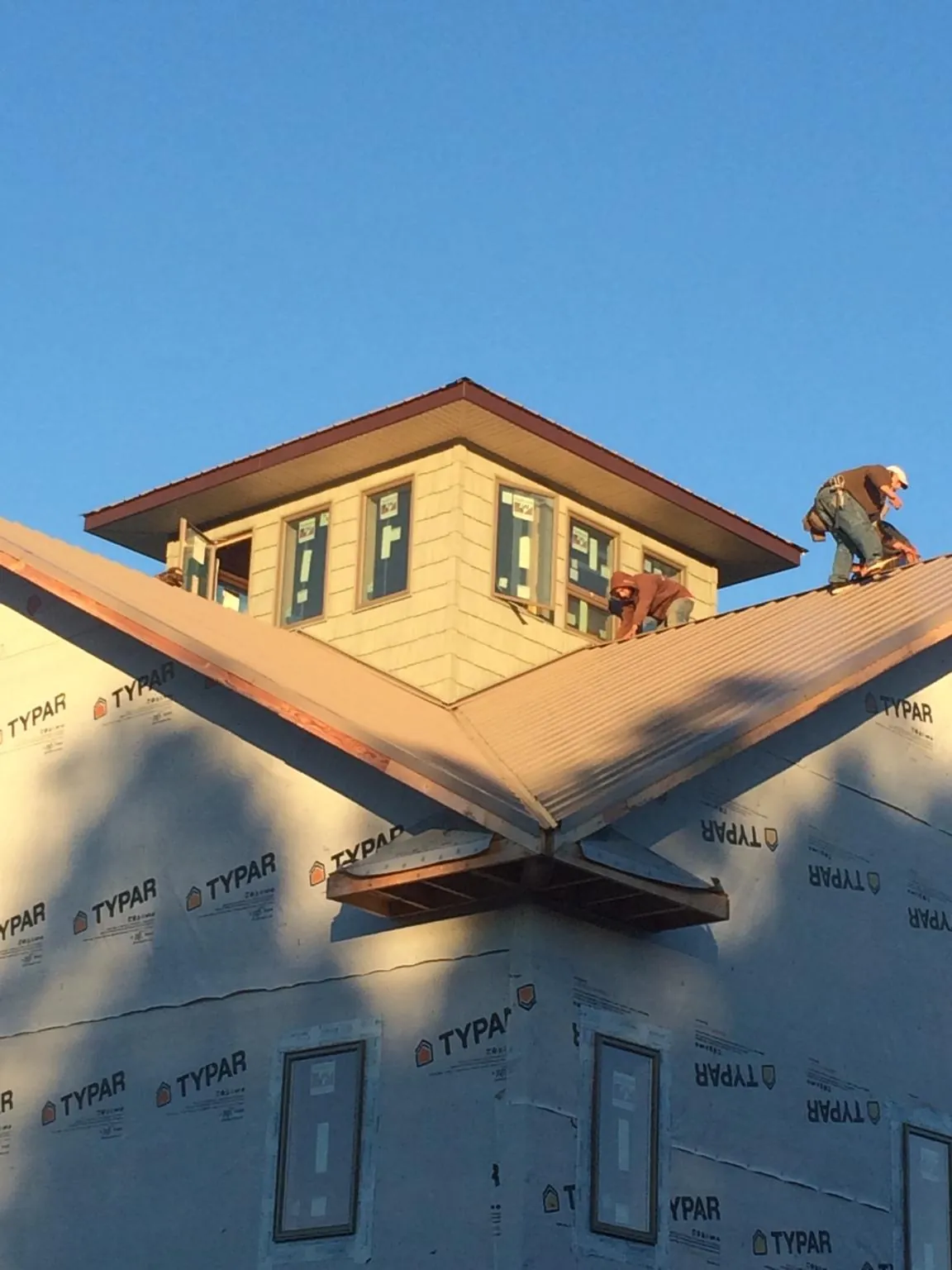 Roofers working around a rooftop cupola on a new metal roof at sunset — Roof Waterproofing in Fiatt by Roofing Brothers